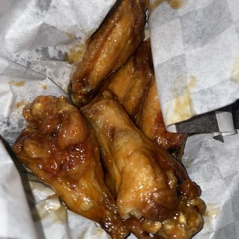 Twisted Wings  - Stingin honey garlic wings - Four honey garlic chicken wings are shown in a paper-lined container, coated with a glossy sauce. - Chicken Wings Near Me - Indianapolis, Indiana