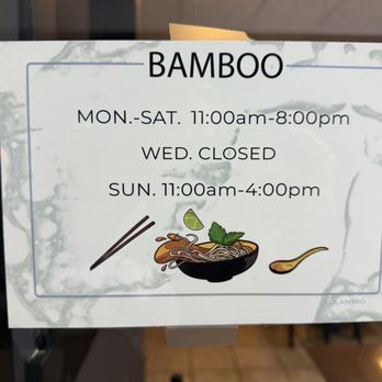 Bamboo by Kulantro - Hours as of 11.25.2025 - The sign provides the business hours for Bamboo, a Vietnamese restaurant, indicating it is open Monday to Saturday from 11:00 am to 8:00 pm, closed on Wednesdays, and open on Sundays from 11:00 am to 4:00 pm. The sign includes a graphic of a bowl of noodles with chopsticks, a lime wedge, and a spoon, set against a background that appears to be a window or glass door. - Vietnamese Near Me - Albuquerque, New Mexico