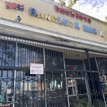 New Bangluck Market - Front entrance to the market on Reseda Bl gated up with broken signage and a decaying facade. - Fruits & Veggies Near Me - Reseda, California