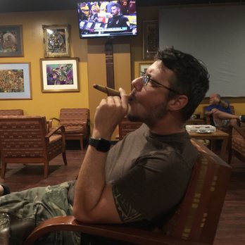 Primo Sigaro - a man smoking a cigar in a restaurant - Wine Bars Near Me - Jacksonville, Florida