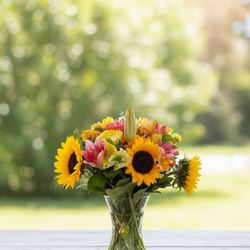 Yunza Florist - Cheerful sunflowers and pink lilies arranged in a clear vase -- a radiant gift that brings sunshine to any space. Handcrafted in Markham