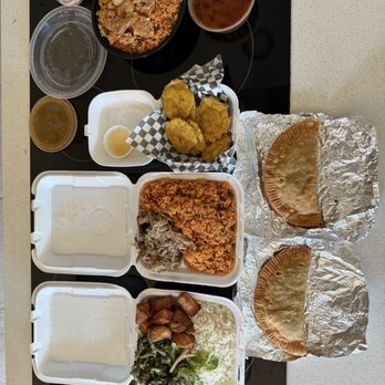 Phoenix Coqui - Assorted Puerto Rican cuisine with rice, fried plantains, empanadas, and beverages displayed on a table. - Puerto Rican Near Me - Phoenix, Arizona