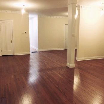 Demo Workers - empty living room with wood floors - Spacious living area with hardwood flooring, cream walls, and minimal decor, featuring multiple doorways and a brick fireplace. - General Contractors Near Me - Hubbard, Illinois