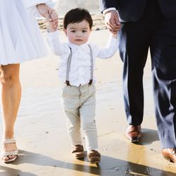 Venya Manzyuk Photography - Young boy holding his parent's hands while walking at the beach.