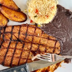 Salsa Tex Mex - Asado de Puerco - Grilled marinated pork tenderloin on a bed of ancho sauce. Served with Spanish rice, black beans, and fried plantain.