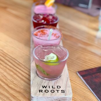 Wild Roots - a row of different drinks on a wooden table - Distilleries Near Me - Portland, Oregon Wild Roots - a row of different drinks on a wooden table - Distilleries Near Me - Portland, Oregon