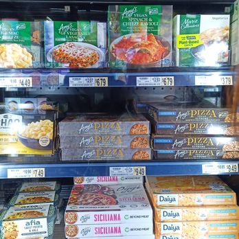 Wegmans - Frozen food products are arranged on supermarket shelves, including ravioli, pizza, and cheese. The packaging displays brand names and product details, with price tags visible below each item. The shelves are organized with multiple brands and varieties of frozen meals and ingredients, typical of grocery store displays. - Grocery Near Me - Niagara Falls, New York
