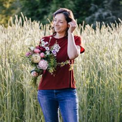 Strawberry Moon Blooms - Sara, farmer-florist of Strawberry Moon Blooms in front of our rye cover crop field with an early Spring bouquet.