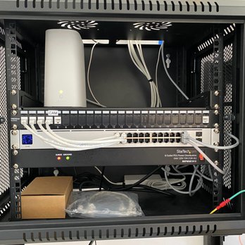 Starlight Tech - New switch and patch panel installed - A network equipment rack contains a router, a power distribution unit, and various cables, with some components mounted and others stored inside. - Telecommunications Near Me - Laguna Niguel, California