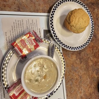 Black Bear Diner Morris - A bowl of clam chowder with a spoon, served with saltine crackers and a biscuit on separate plates at a restaurant table. - Diners Near Me - Morris, Illinois