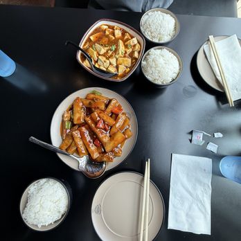 Mr Dumpling - Mapo tofu extra side of rice and eggplant in garlic sauce - A dining table set with two bowls of white rice, a plate of stir-fried dish, and a bowl of Mapo Tofu, with chopsticks and a napkin. - Dim Sum Near Me - Eugene, Oregon