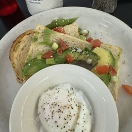 Avocado toast with fresh tomatoes and green onions. One side of a poached egg, and a cup of coffee!