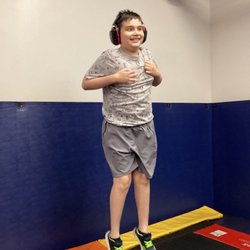 Merlin Day Academy - Child wearing headphones and smiling while jumping on a large trampoline in Merlin Day Academy's gym.
