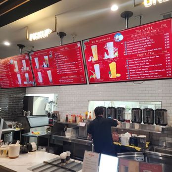 TP Tea - A barista is working behind a counter in a boba tea shop, with digital menu screens displaying various milk teas and fruit teas. - Bubble Tea Near Me - Millbrae, California