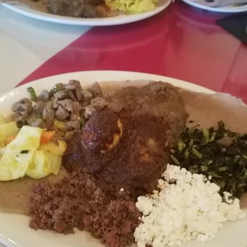 Addis Abeba Ethiopian Restaurant - Taste of Ethiopia  platter: Injera, cabbage, ground beef, beef tibs, goat curry, chicken curry, goat cheese & greens. - Ethiopian Near Me - Richardson, Texas