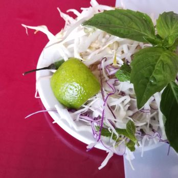 Pho Long Phung - a bowl of food with a lime and sprouts - Vietnamese Near Me - Montreal, Quebec