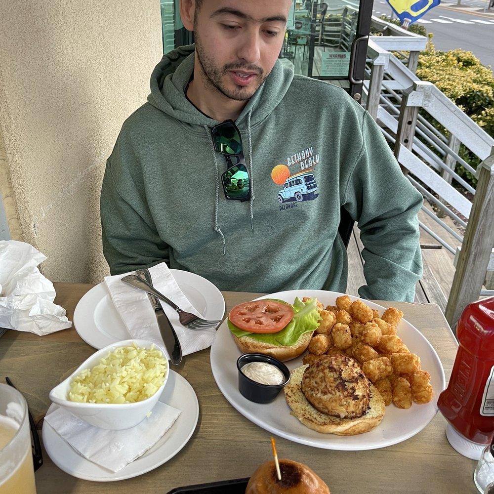 Starboard Raw - a man sitting at a table with a plate of food - American Near Me - Dewey Beach, Delaware Starboard Raw - a man sitting at a table with a plate of food - American Near Me - Dewey Beach, Delaware
