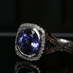 Dominion Jewelers - Bezel-set round tanzanite stone in a square halo with twisted split shank band