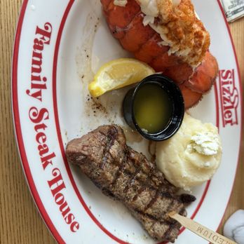 Sizzler - Steak & Lobster - A seafood and steak meal featuring a lobster tail with butter, a grilled steak, mashed potatoes, and a lemon wedge on a Mel's Diner plate. - Seafood Near Me - Merced, California