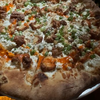 Post - a pizza on a plate with a lit candle in the background - New American Near Me - Hamilton, Massachusetts