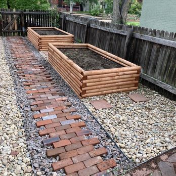 Vista Landscape Development - Brick walking path surrounded by quarry rock to the side gate.  Plantar boxes. River rock surrounding the boxes. - Landscaping Near Me