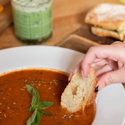 Little Finch - Person dipping a piece of bread in tomato soup