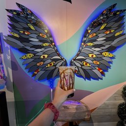 a hand holding a coffee cup with wings painted on it a hand holding a coffee cup with wings painted on it