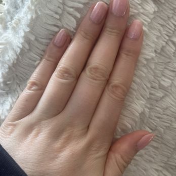 Old Town Nails - Before - A hand with neatly manicured nails painted in a light, glossy pink shade is resting on a soft, textured white fabric. - Nail Salons Near Me - Chicago, Illinois