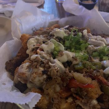 Ormond Garage - A dish featuring fried food topped with creamy sauce, chopped green onions, and vegetables, served on a paper-lined plate. - New American Near Me - Ormond Beach, Florida