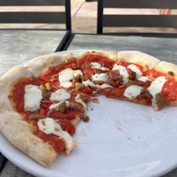 Wood fired pizza with sausage mozzarella cheese and red sauce Wood fired pizza with sausage mozzarella cheese and red sauce
