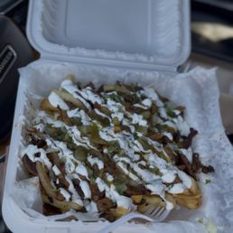 Nacho fries: pastor, green sauce, nacho sauce, grilled onions, sour cream and cilantro.