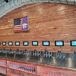 a row of beer taps in front of a wooden wall