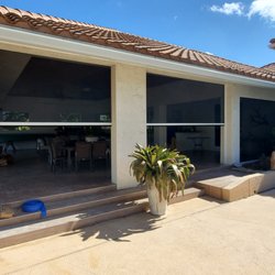 Harrison Awnings - Motorized Screens with white housings and black insect screen material in a half way open/closed position