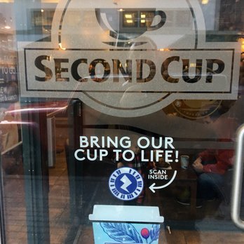 Second Cup - a cup of coffee in front of a window - Coffee & Tea Near Me - Banff, Alberta