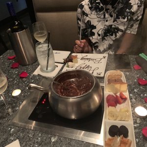 Photo of The Melting Pot - Atlanta, GA, United States. A bottle of sparkling wine , rose petals , and dessert