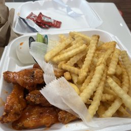 chicken wings and fries in a styrofoam container chicken wings and fries in a styrofoam container