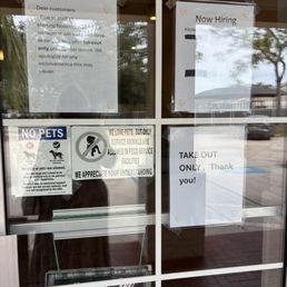 Take Out Only - No more dine in - Several signs are taped to the glass door, including notices about takeout only, staffing shortages, pet policies, and a hiring announcement.