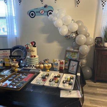 Layered with Sugar - a table with a cake and balloons - Custom Cakes Near Me