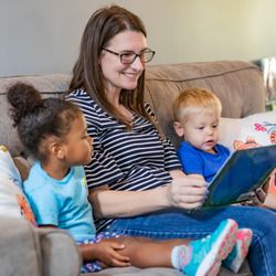 Mt. Elizabeth Academy - School Director reading a book to 2 children on a couch