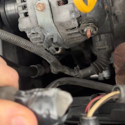 Cartec Automotive Services - This is a picture of the alternator wire completely disconnected and dangling inside the engine bay with electrical tape wrapped around it.