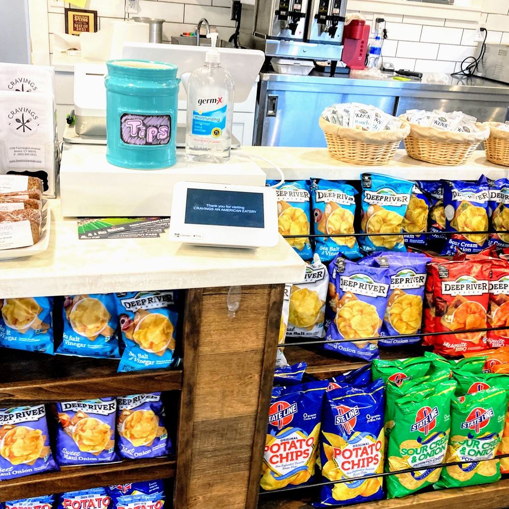 Cravings An American Eatery - Close up of the check out counter, with sanitzer, tip jar, and STATE LINE CHIPS!! - Delis Near Me - Bristol, Connecticut