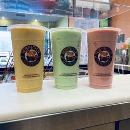 Mango Strawberry Smoothie - Three smoothies in clear cups with Teapioca Lounge logos, featuring yellow, green, and pink drinks, on a white surface.