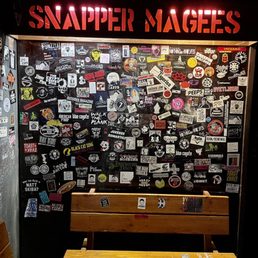a table and benches in front of a wall covered with stickers