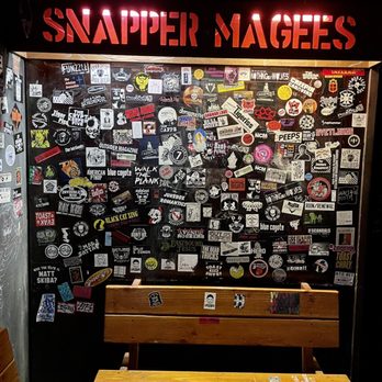 Snapper Magee's - a table and benches in front of a wall covered with stickers - Dive Bars Near Me - Kingston, New York