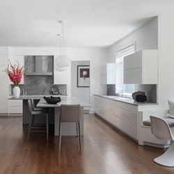 Unadorned flat panel doors create a soothing environment in light-reflecting glossy white on the perimeter, with soft matte gray on the bar