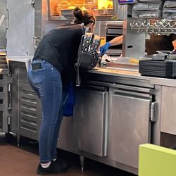 Del Taco - Worker standing over the food area on her phone with her backpack she placed on area where food was being made!
