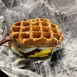 Mugs Coffee Bar - Delicious Waffle Breakfast Sandwich with bacon,egg, and cheese. Also, with a touch of sprinkled sugar on top.