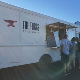 a group of people standing in front of a food truck a group of people standing in front of a food truck