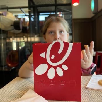 Chick-fil-A - ows a young girl sitting at a table with a sign in front of her - Fast Food Near Me - Laurel, Mississippi