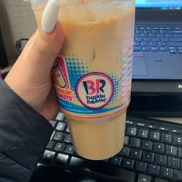  a hand holding a cup of iced coffee